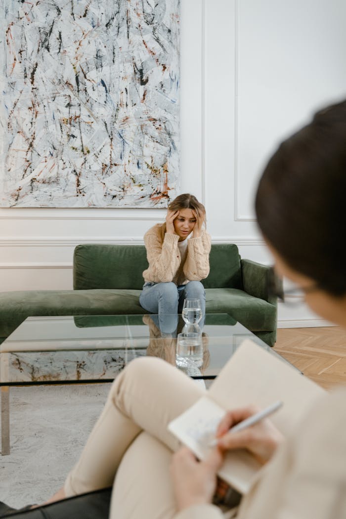 Home A woman looks distressed during a therapy session indoors, emphasizing mental health support.