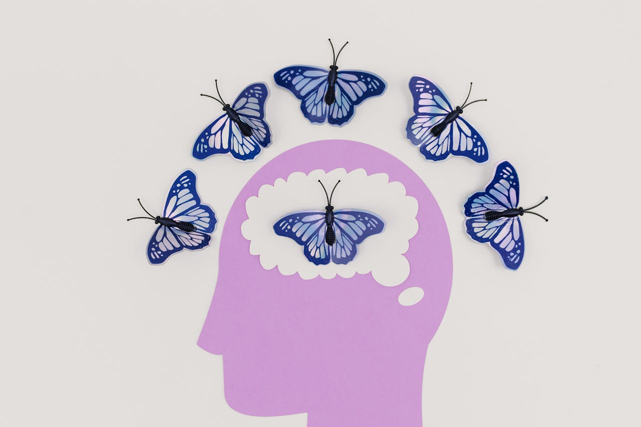 Home Creative illustration of butterflies representing thoughts over a brain silhouette.